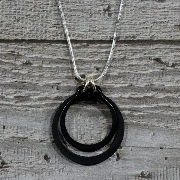 Black and Silver circlips pendant close up by factory floor jewels