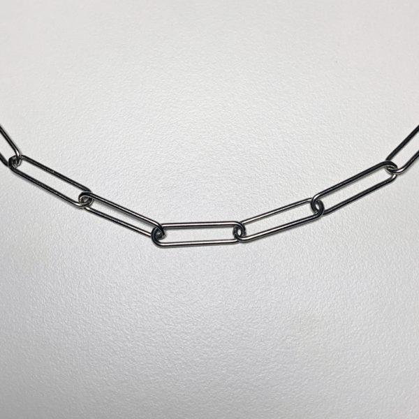 close up of a steel paperclip style chain on a white background