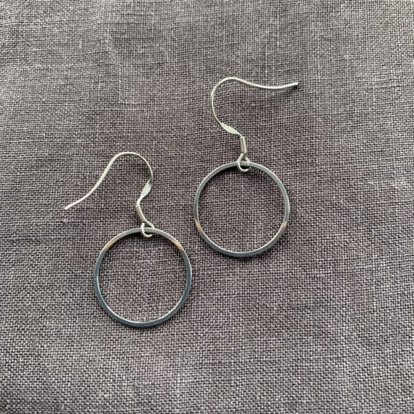 steeel circle earrings on a grey linen background