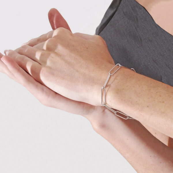 photo of a woman's arm to show a stainless steel paperclips style bracelet being worn. Her shoulder is just within the shot but not her face