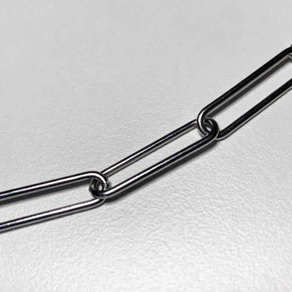 a close up photo of 3 oblong links of a stainless steel paperclip style chain on a white background