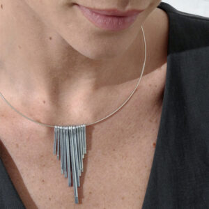 A silver art deco inspired neck cuff by Factory Floor Jewels worn by a women wearing a black jacket