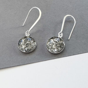 Silver dangle earrings which show off the beauty of reclaimed aluminium fragments to evoke the feeling of the night sky. They are photographed on a grey background