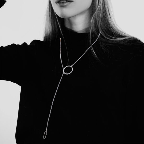 a women in a black polo neck jumper is wearing a Steel and Brass Lariat by Factory Floor Jewels.