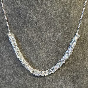 Close up of a 'Soiree' pendant on a grey velvet jewellery display bust