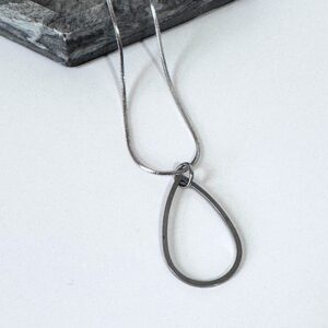 steel teardrop pendant on white counter and a grey mottled dish