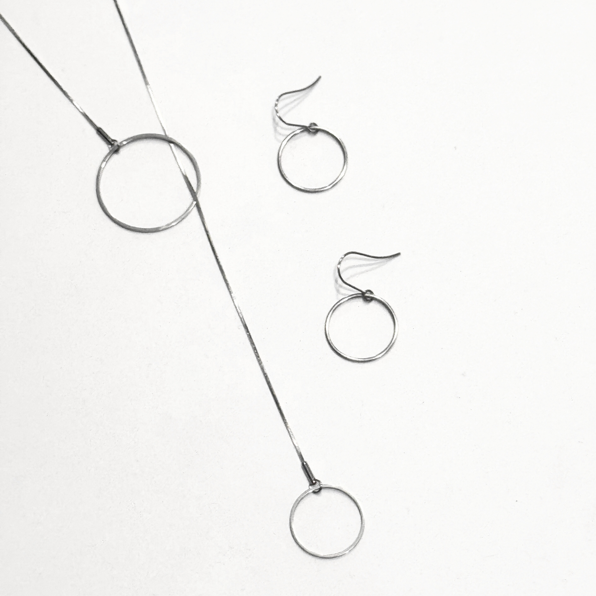 H5O steel circles lariat and circles earrings on white background