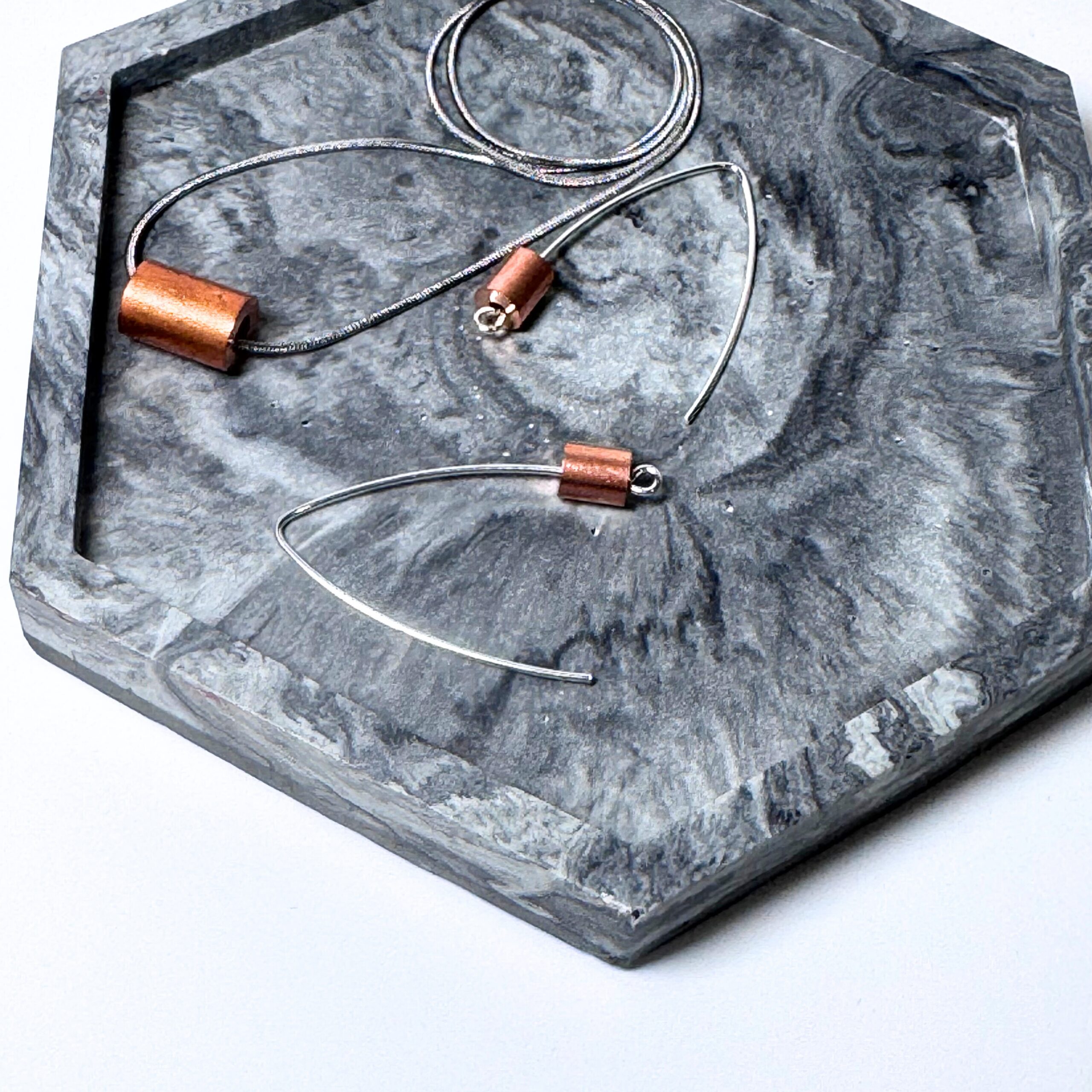 Copper, Steel and Silver 'weights' jewellery collection of earwires and pendant on a grey motled tray